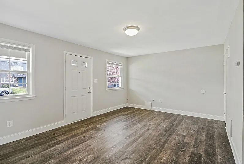 Bright and airy living room with elegant wood flooring and ample natural light from large windows.