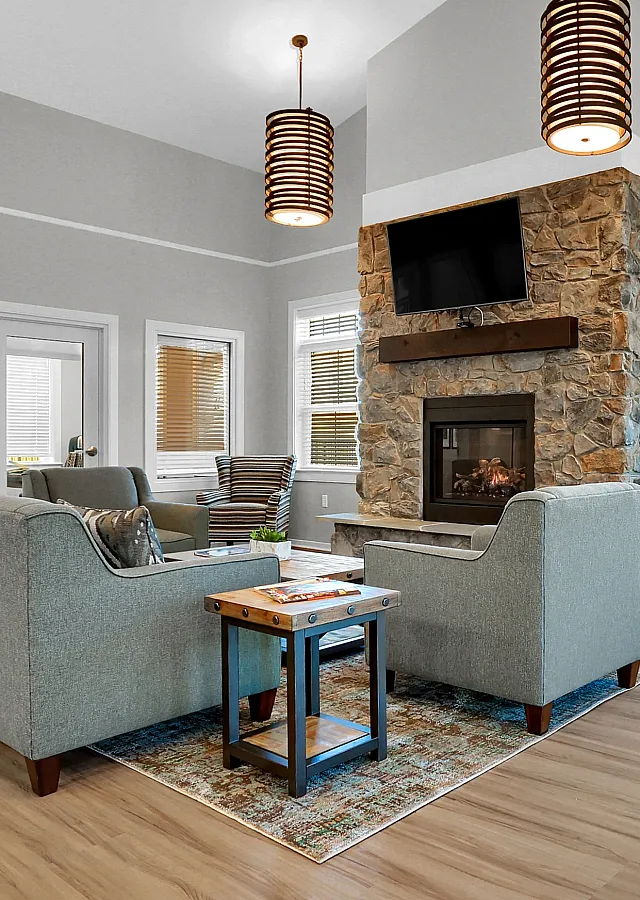Inviting living room with modern stone fireplace, stylish pendant lights, and plush seating, perfect for relaxation.