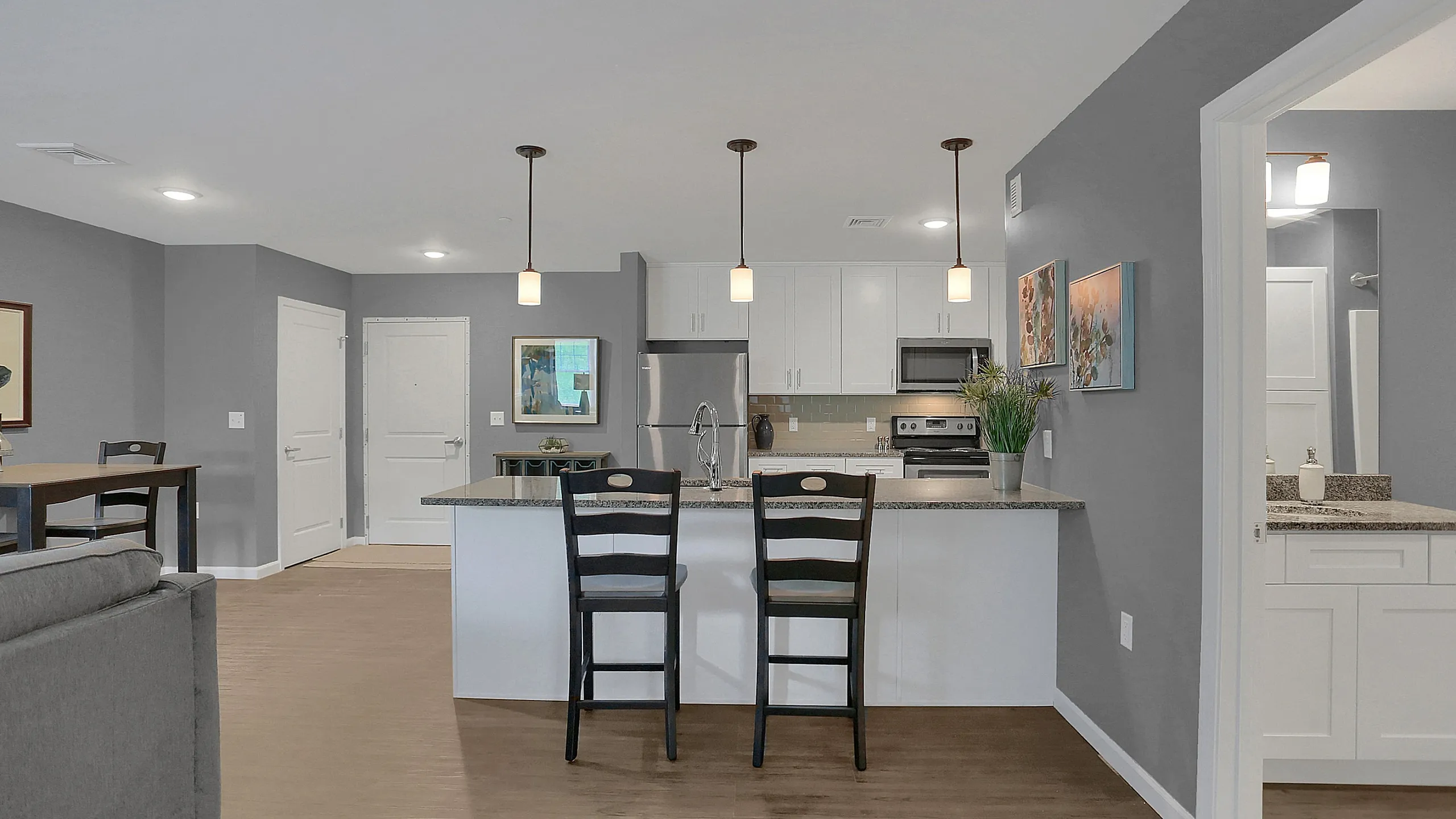 Bright and modern open-concept kitchen and living area, featuring sleek countertops, stylish pendant lighting, and contemporary decor.