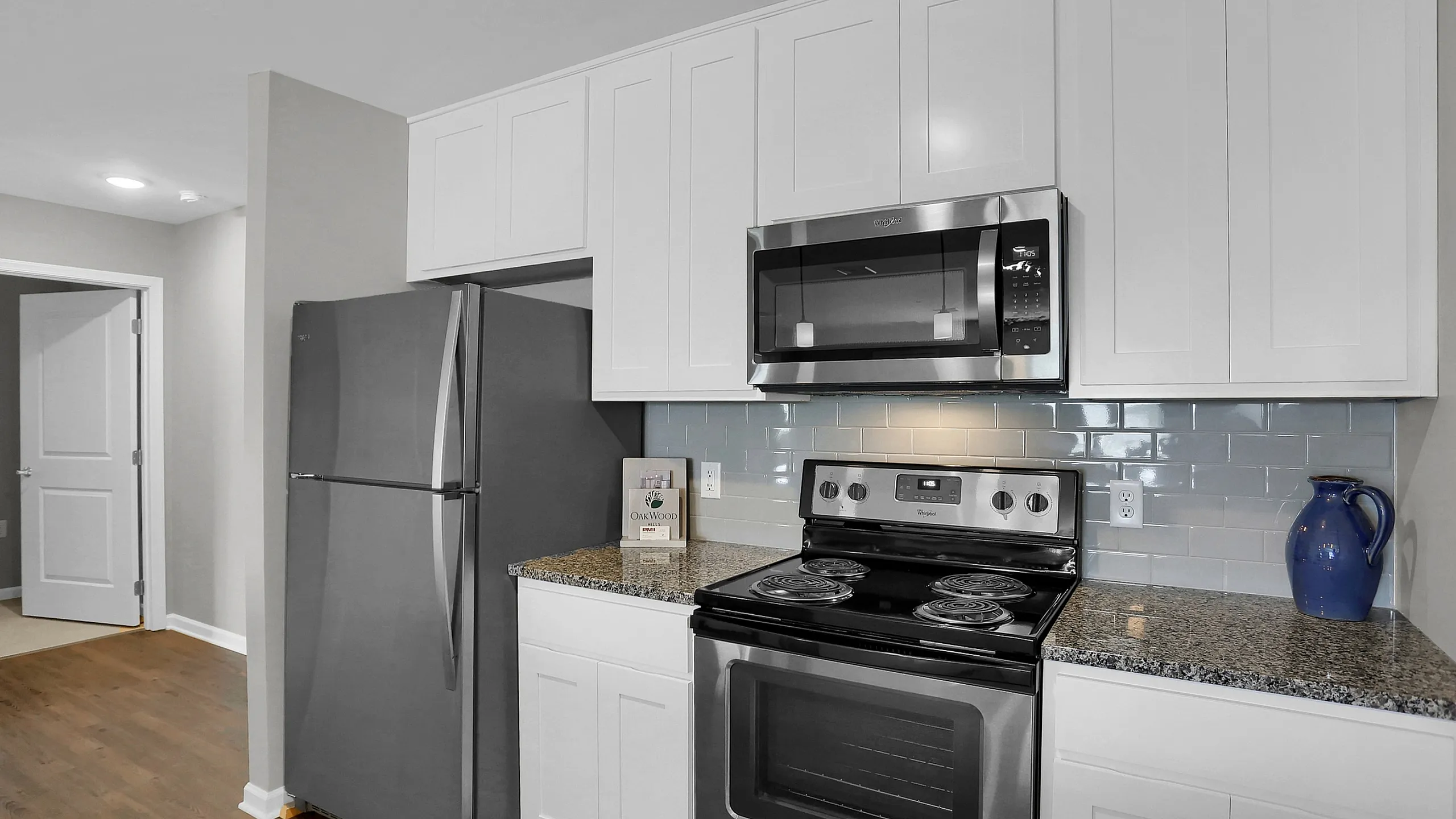 Modern kitchen with sleek stainless steel appliances, elegant white cabinetry, and polished granite countertops.