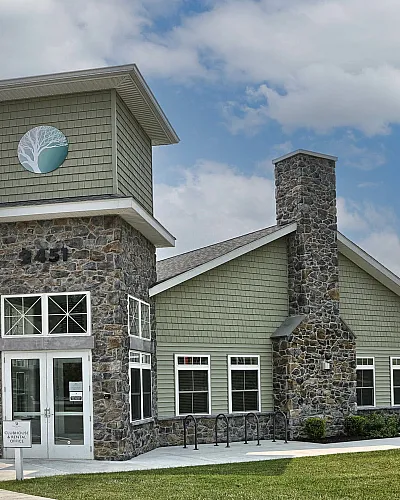 Charming residential building with stone facade, modern architecture, and a welcoming entrance, set against a backdrop of blue skies.