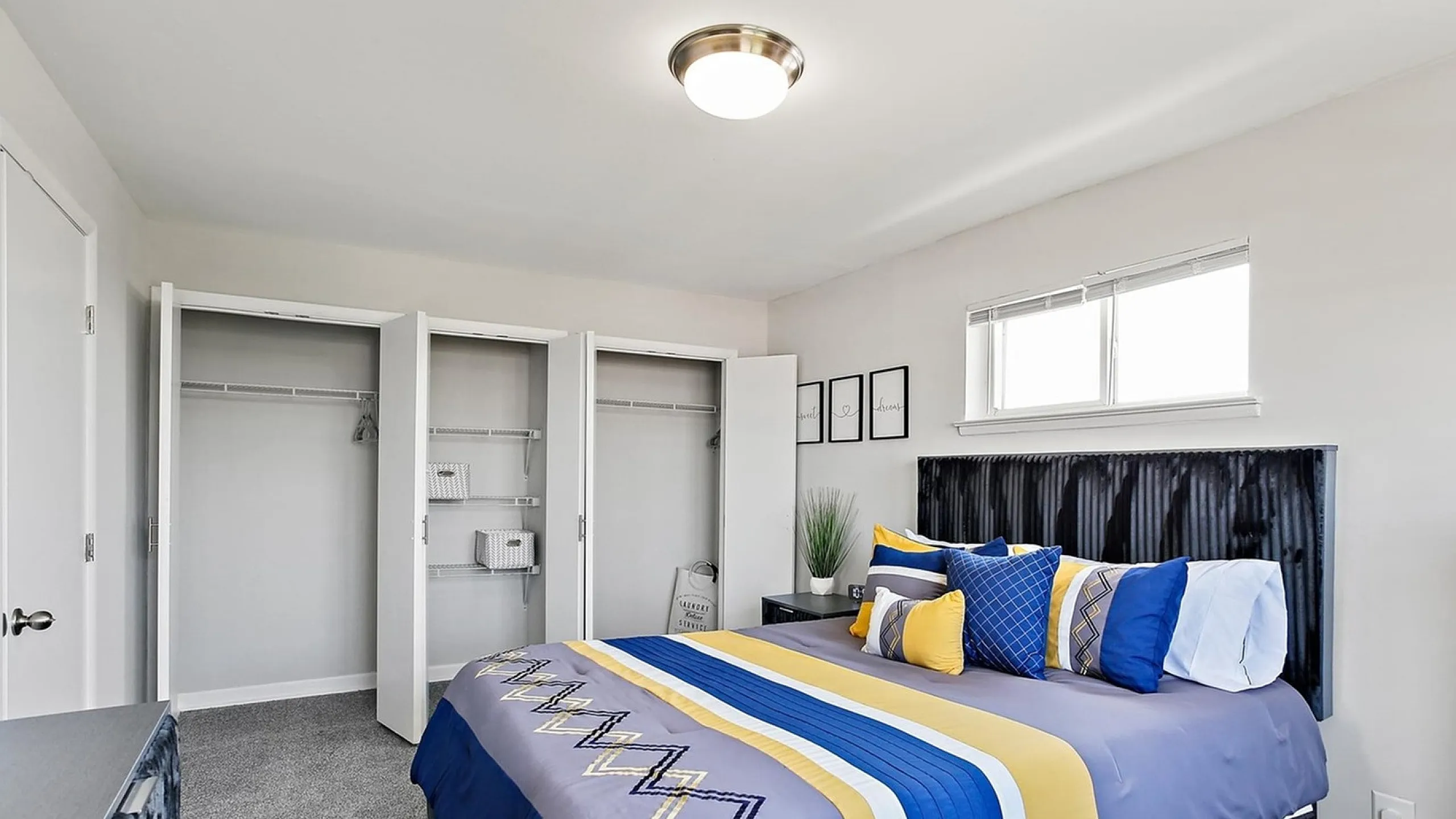 Bright and modern bedroom with a luxurious bed featuring vibrant blue and yellow bedding, spacious closets, and stylish decor.
