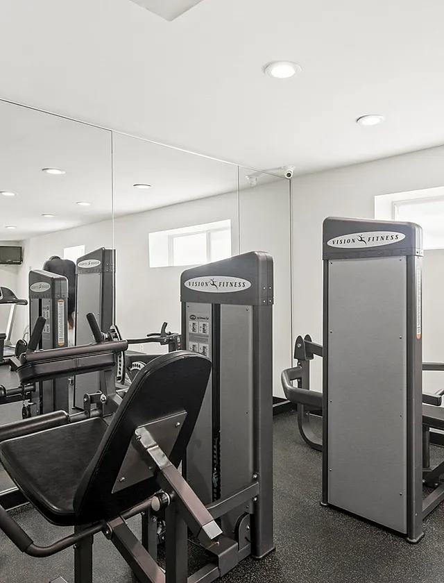 Contemporary fitness room filled with modern exercise equipment, mirrored walls, and ample lighting for an energizing workout experience.