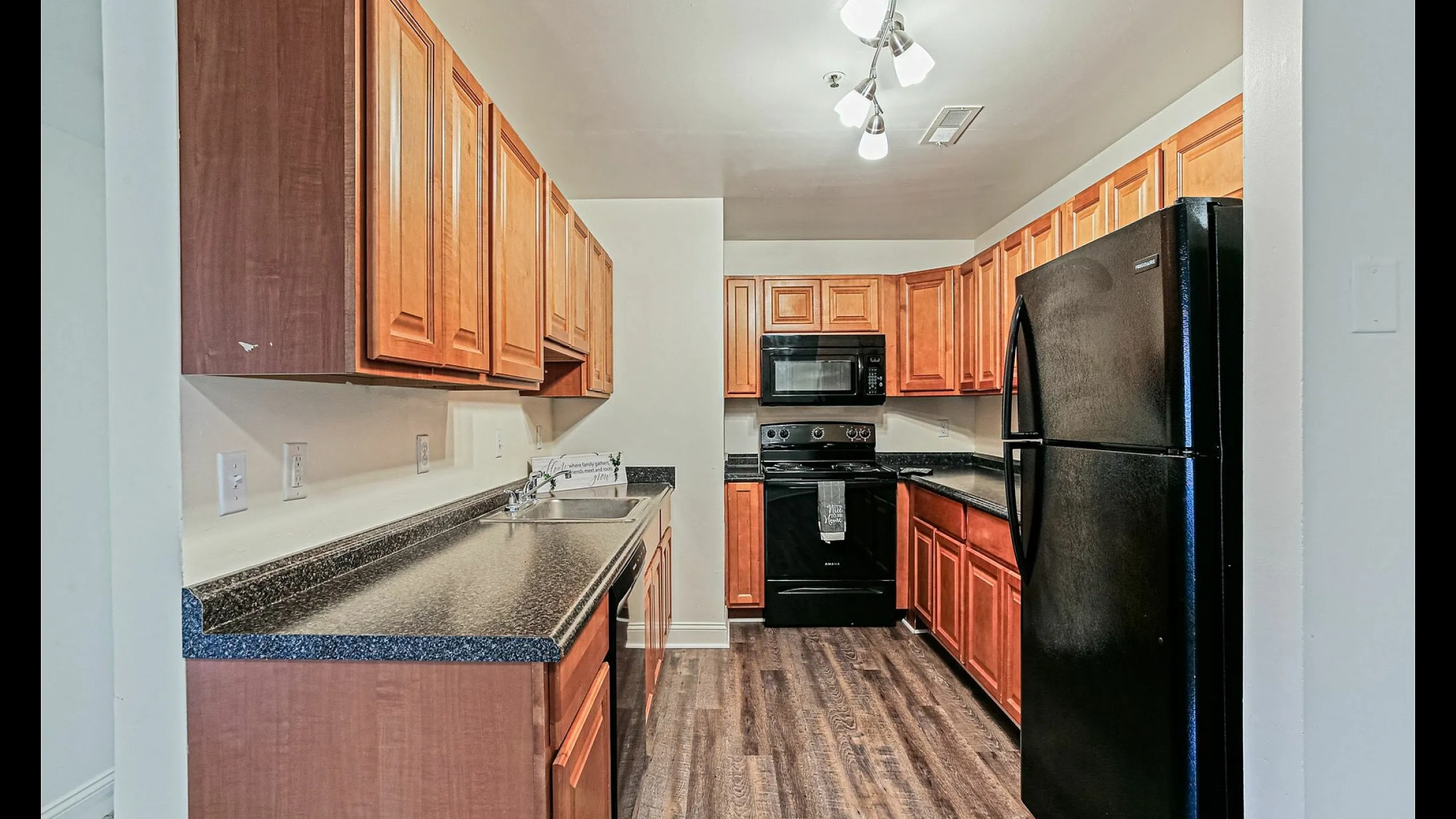 Modern kitchen with sleek black appliances and warm wooden cabinetry, exuding contemporary elegance.