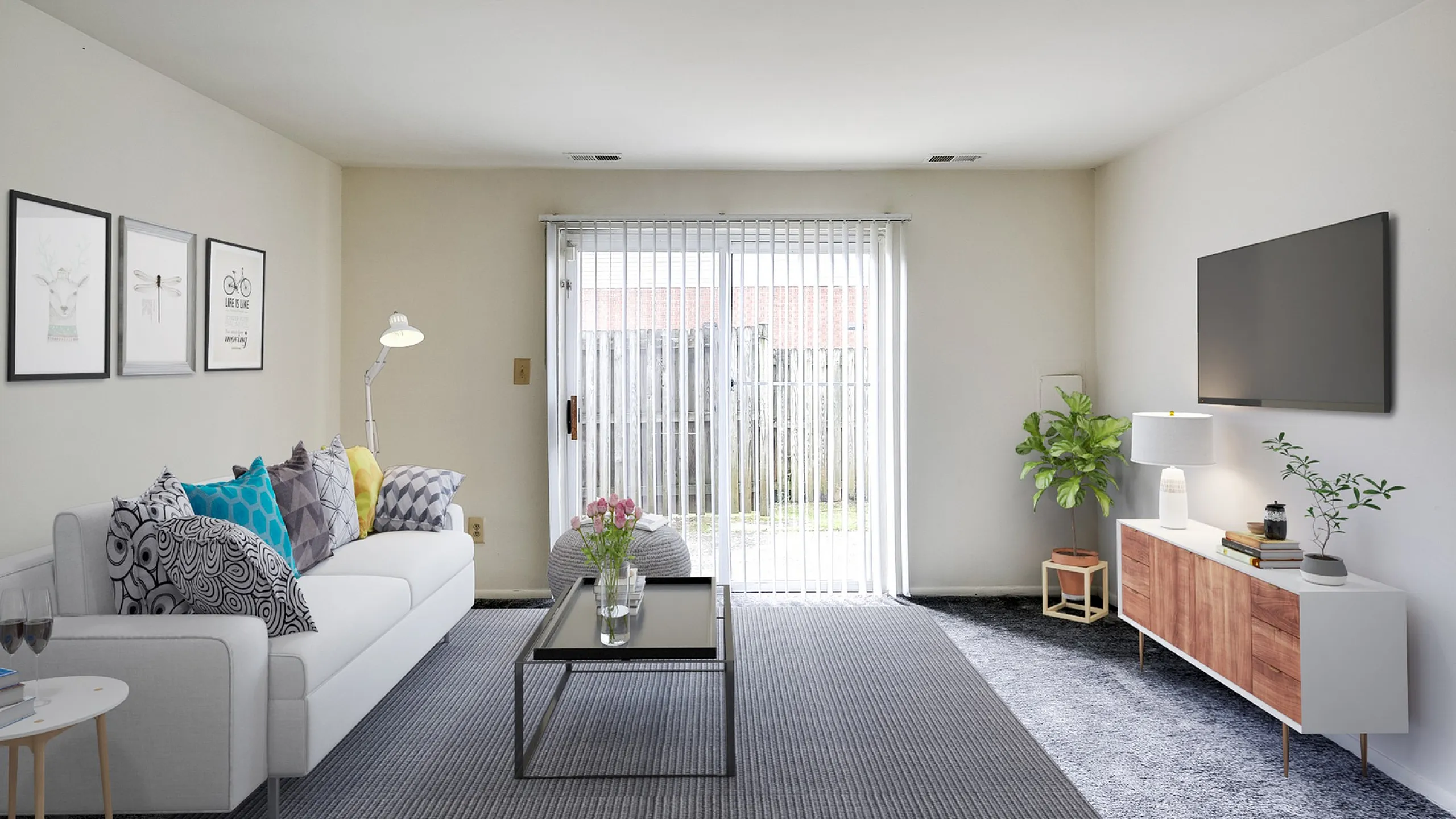 Inviting living room with modern decor, a sleek white sofa with vibrant cushions, stylish coffee table, and light-filled ambiance through sliding doors.