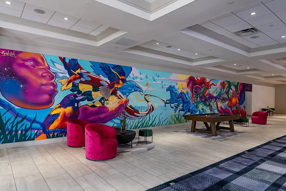 Vibrant mural in a modern lobby featuring dynamic wildlife and surreal imagery, complemented by elegant pink seating in a spacious setting.