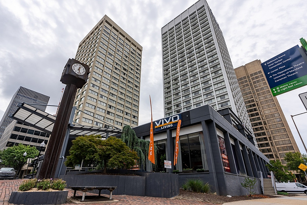 Vibrant urban scene with modern high-rise architecture, featuring Vivo Living apartments, set against a dynamic city backdrop with lush greenery and distinctive clock tower.