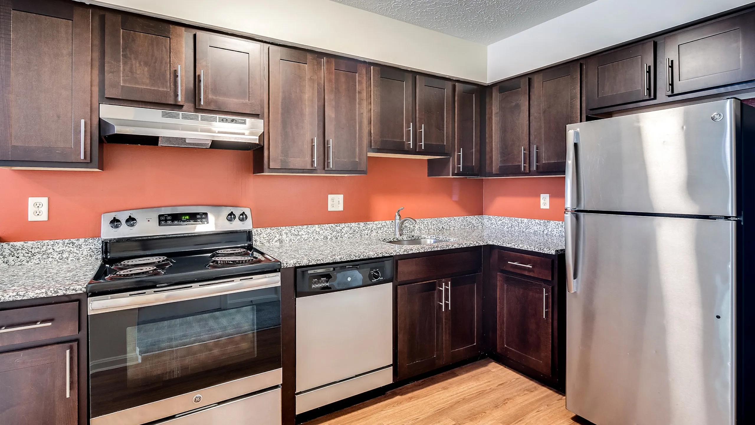 Modern kitchen with sleek stainless steel appliances, rich dark cabinetry, and elegant granite countertops, perfect for culinary enthusiasts.
