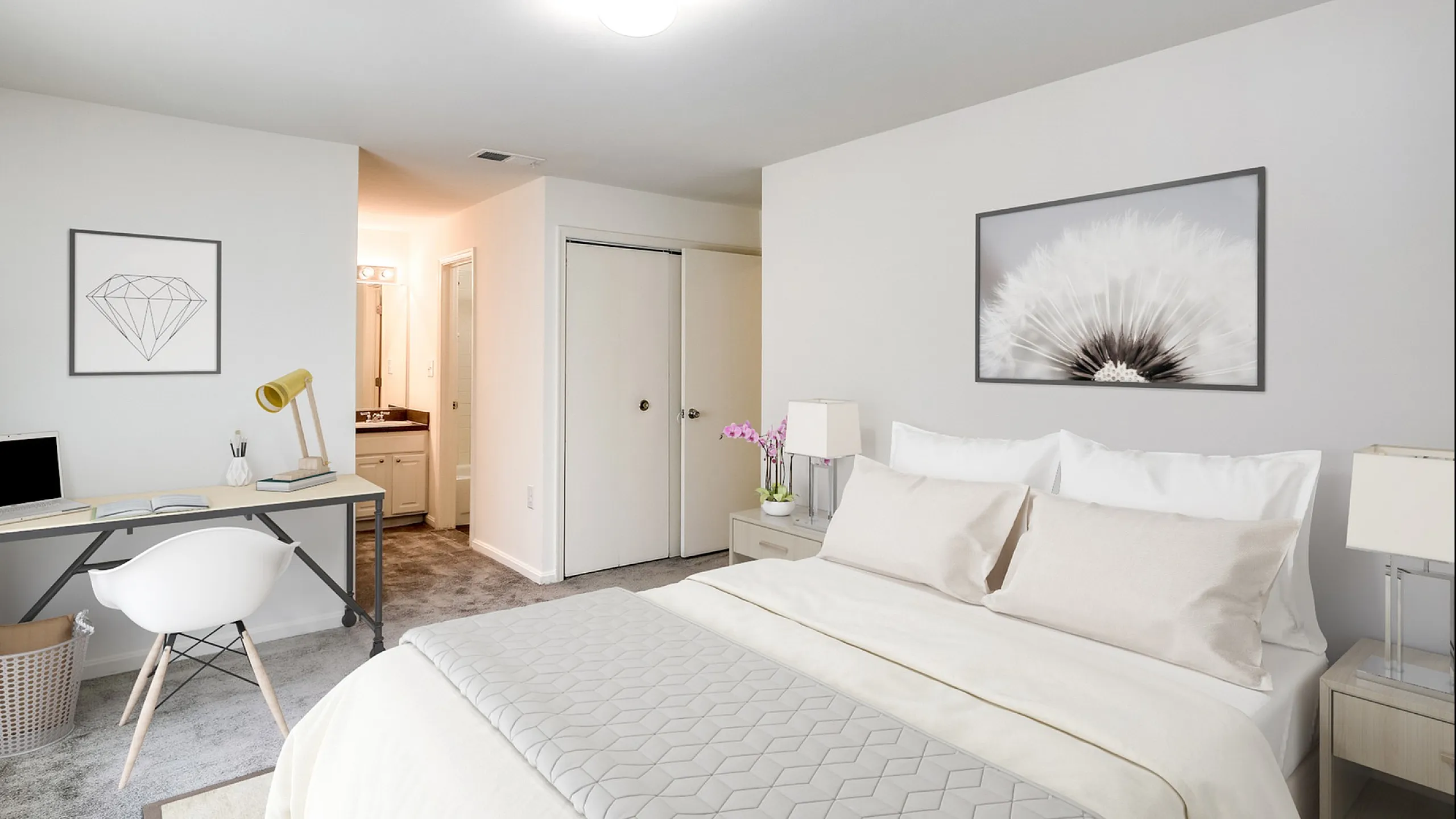 Elegant bedroom featuring a plush bed with neutral linens, a modern workspace with a laptop, and tasteful wall art, creating a serene and cozy atmosphere.