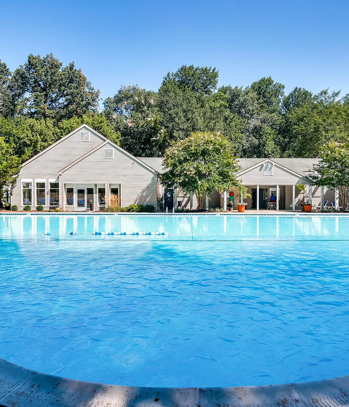 Inviting outdoor pool area with crystal clear water, surrounded by lush greenery and charming residences.