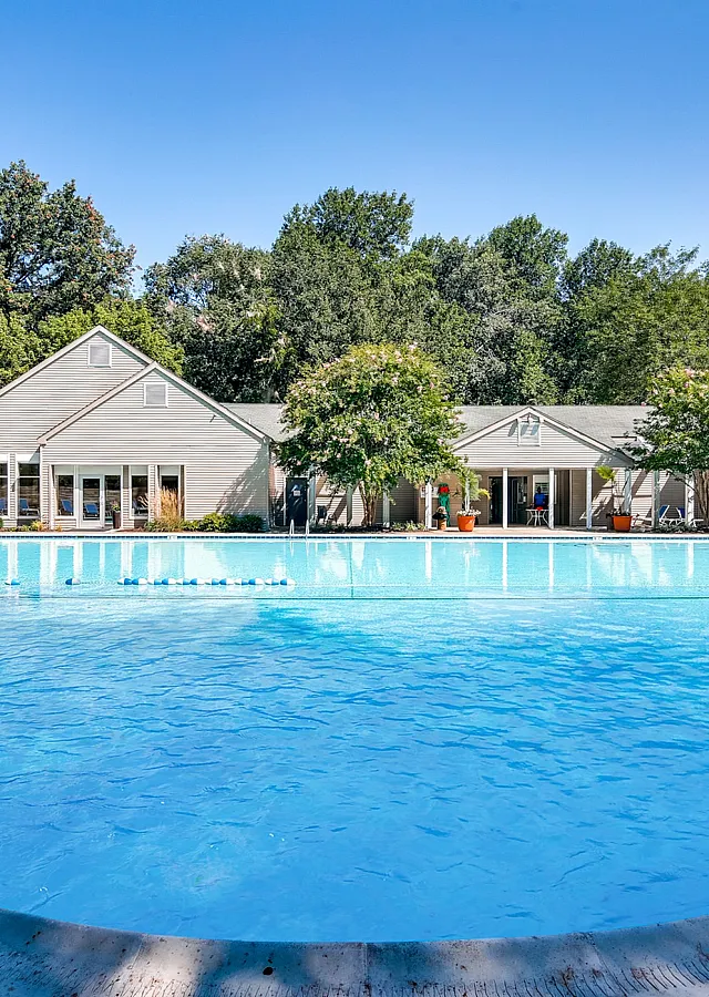 Inviting community swimming pool surrounded by lush greenery and modern clubhouse, perfect for relaxation and recreation.