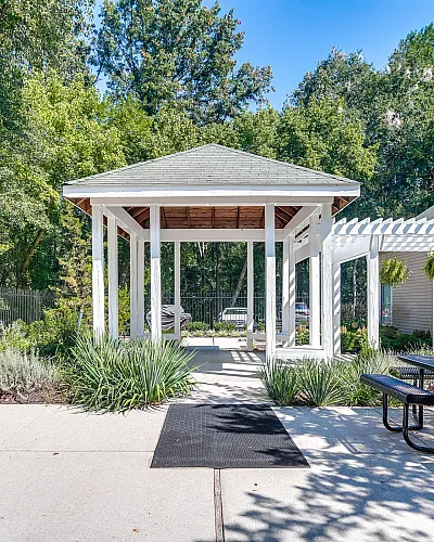 Charming garden pergola with lush greenery, modern benches, and a welcoming pathway, offering serene outdoor living.