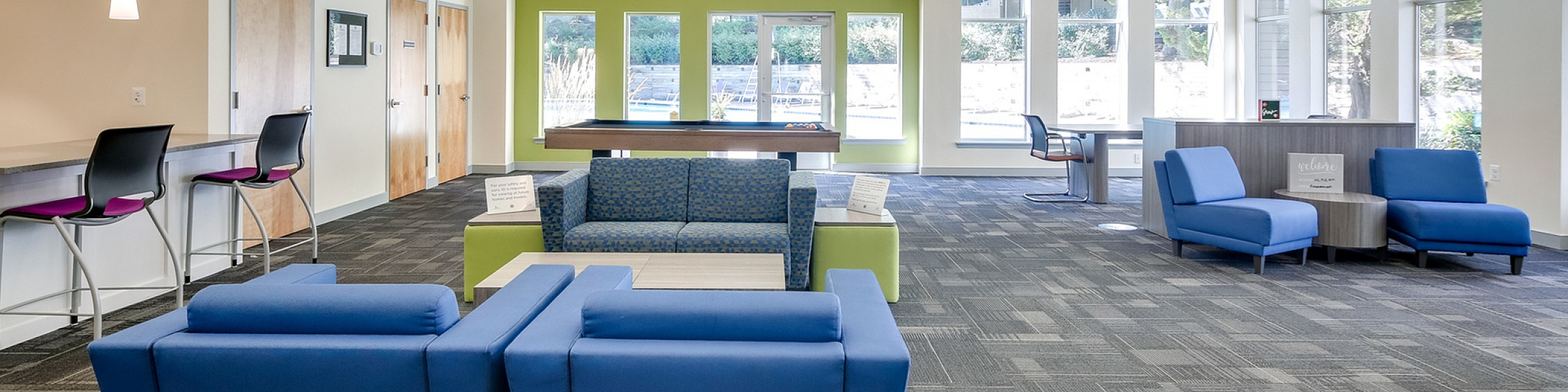 Bright and spacious community lounge featuring modern chandeliers, stylish seating areas, and large windows for natural light.