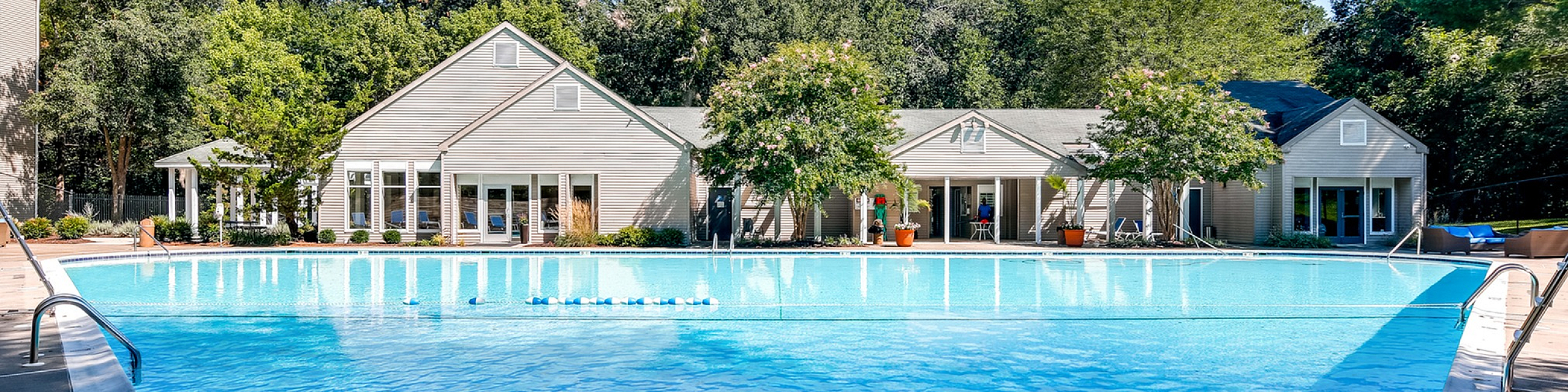 Luxurious apartment amenity featuring a sparkling pool with surrounded by lush greenery, perfect for relaxation and leisure.