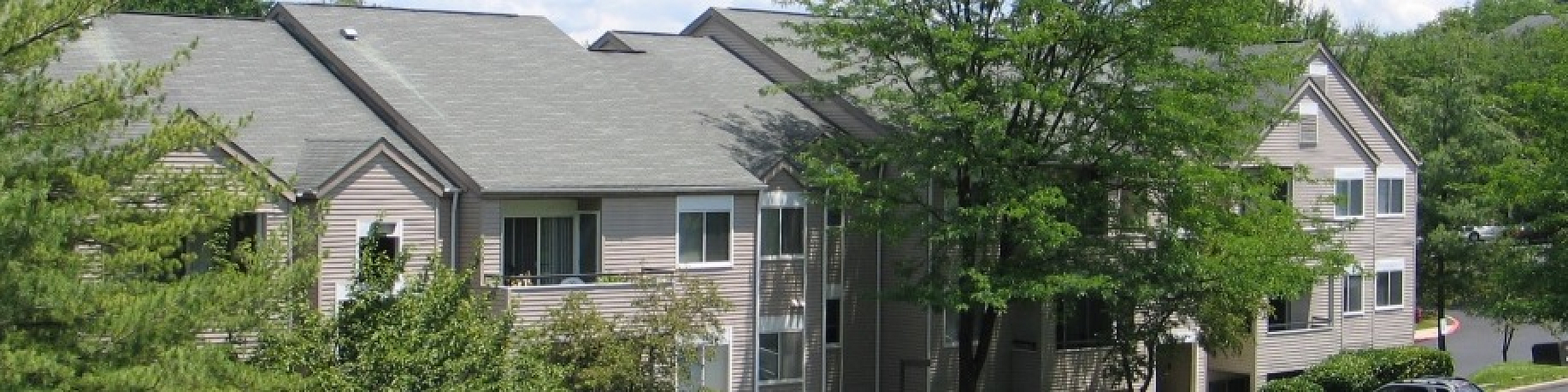 Charming apartment complex surrounded by lush greenery, featuring modern architecture under a bright blue sky.