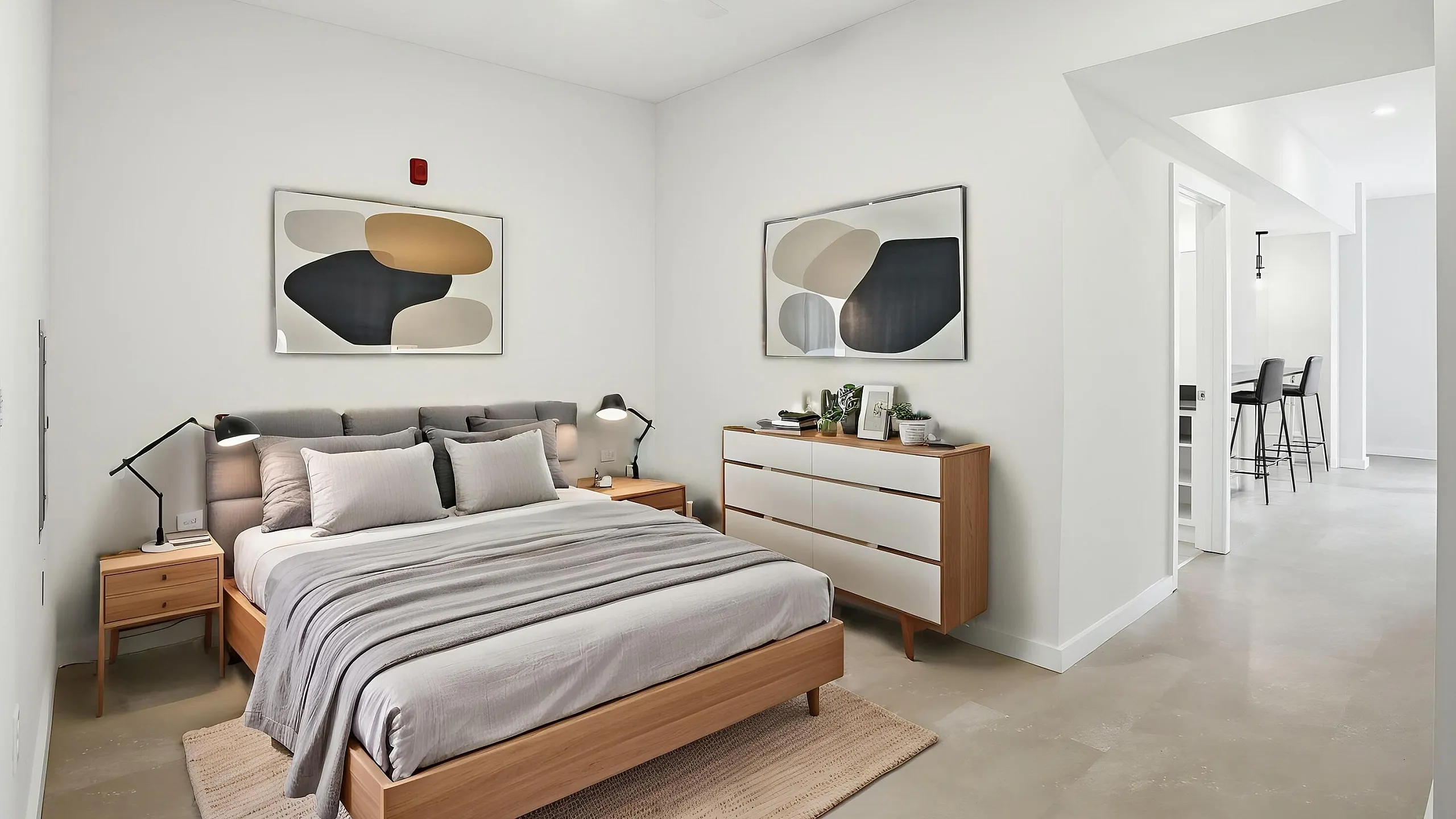 Modern bedroom with elegant minimalist design, featuring a cozy bed and chic artwork, leading to an open dining area.
