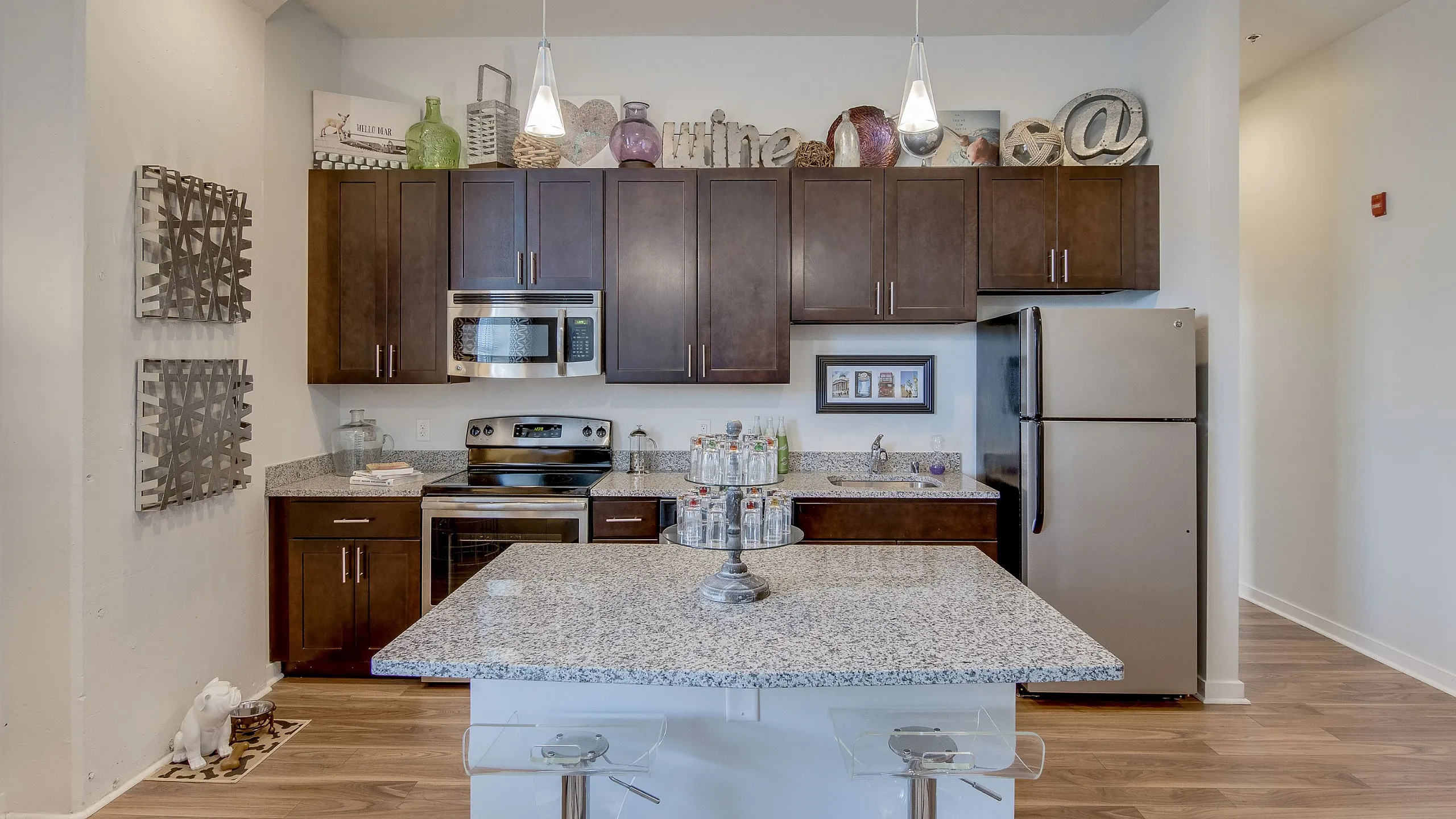Modern kitchen with sleek granite countertops, stylish pendant lighting, stainless steel appliances, and warm wood cabinetry, perfect for culinary enthusiasts.