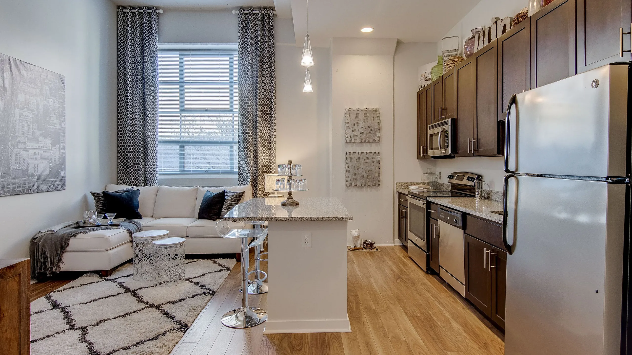 Contemporary open-plan kitchen and living room with warm wooden floors, modern appliances, and chic decor.