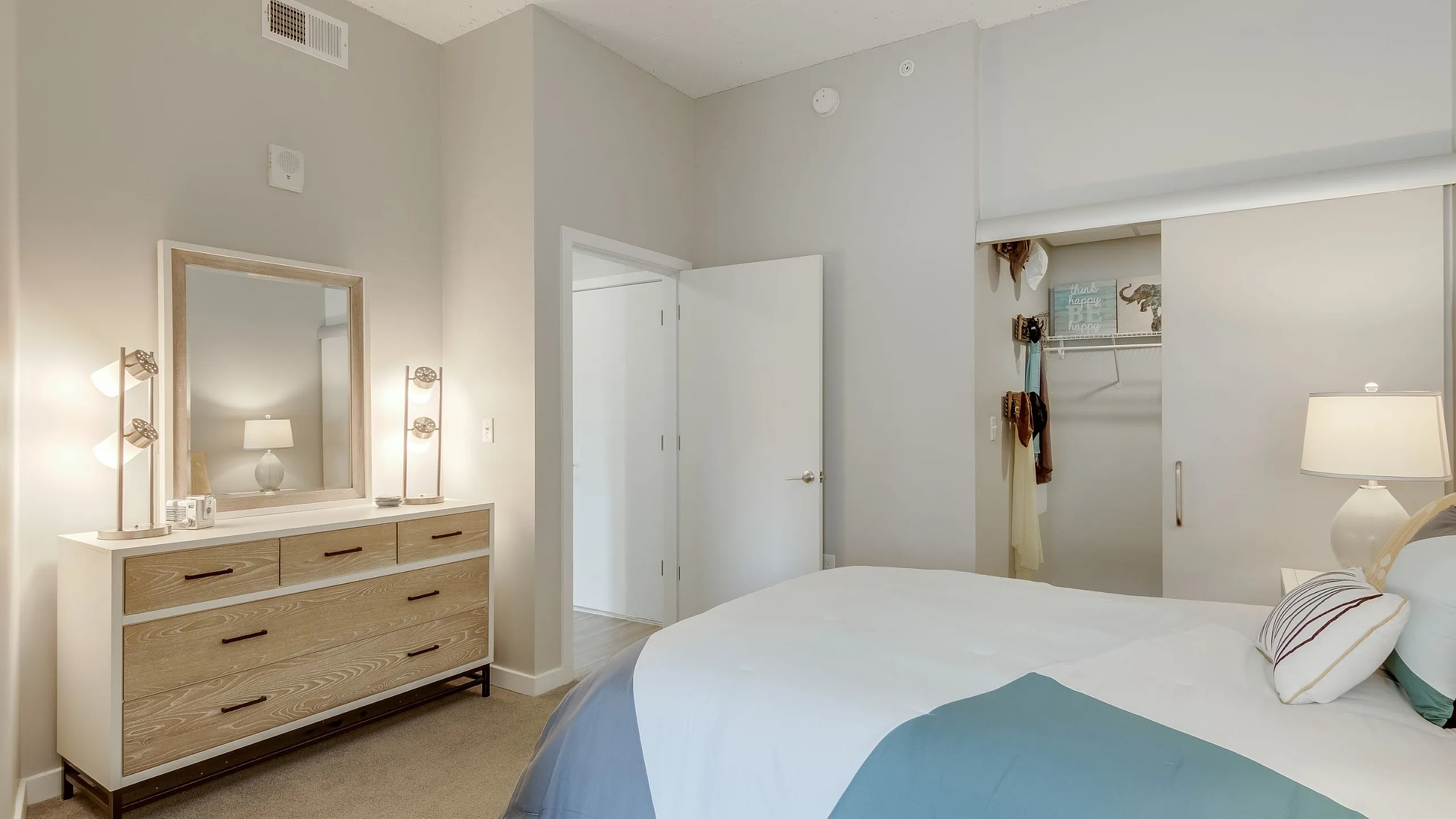 Charming bedroom featuring cozy bedding, elegant dresser with mirror, and spacious walk-in closet.