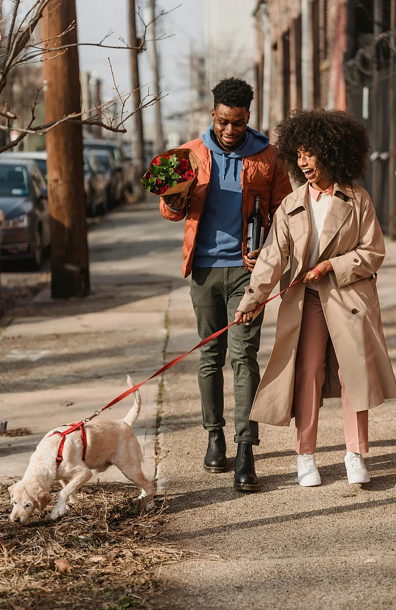 Joyful urban stroll showcasing a couple with a dog on a tree-lined street, embodying vibrant city living.