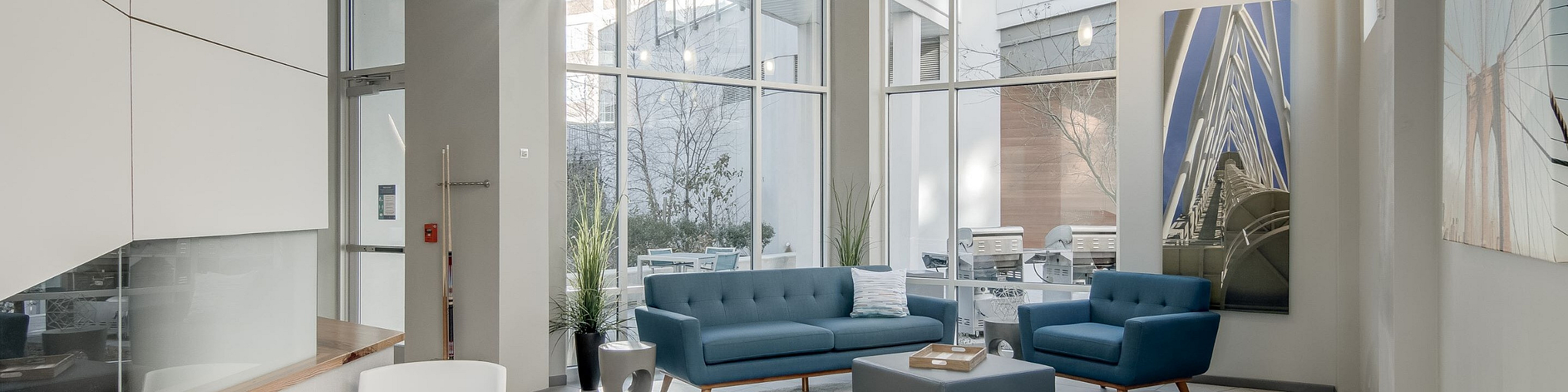 Bright and modern lobby with floor-to-ceiling windows, stylish blue sofas, and contemporary decor, perfect for welcoming guests.