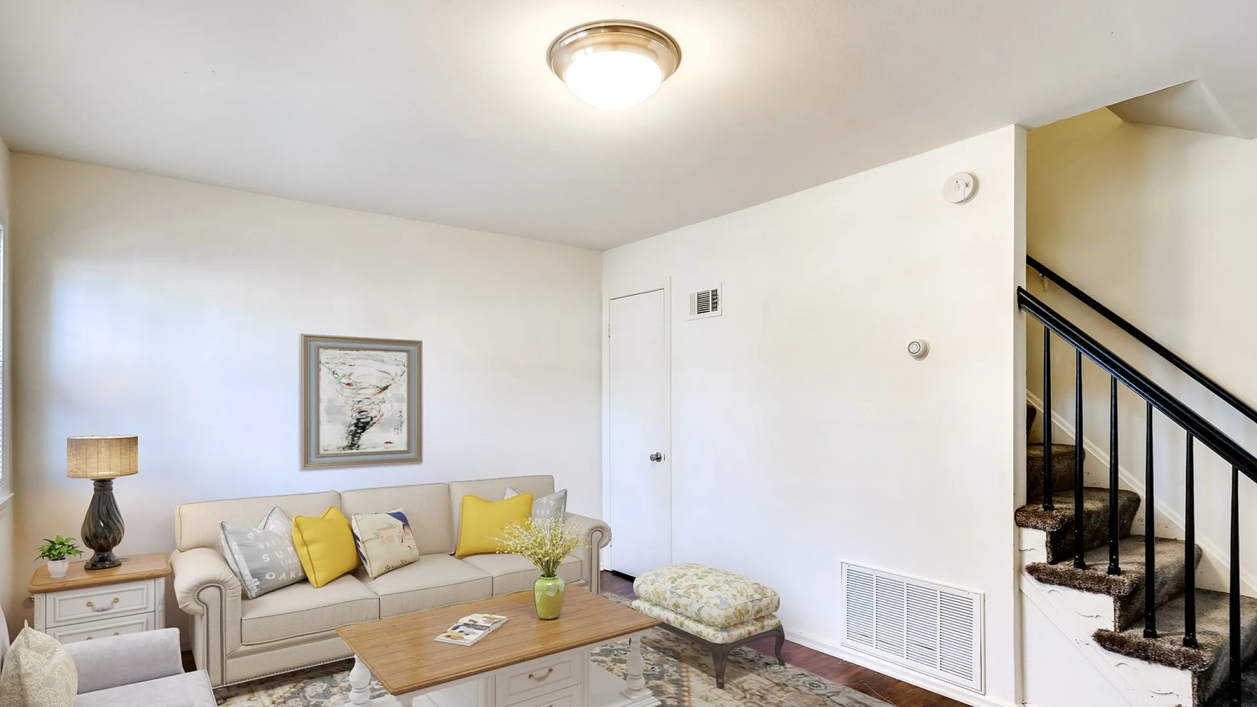 Inviting living room with cozy seating, elegant decor, and a stylish staircase, featuring abundant natural light and warm hardwood floors.