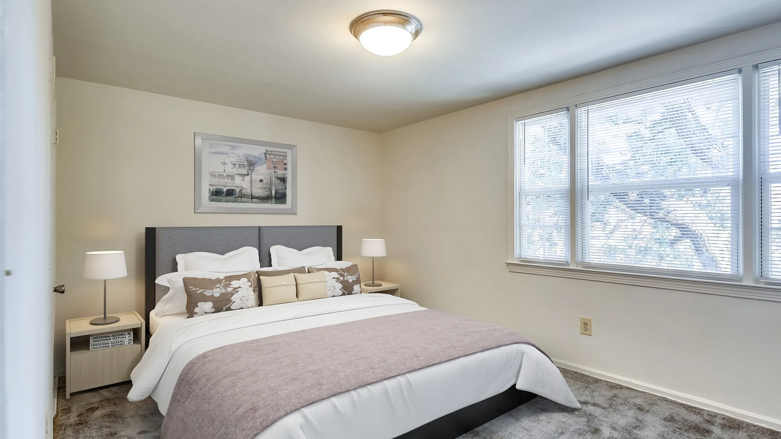 Inviting bedroom with a large window, stylish bedding, and soft lighting creating a cozy and serene atmosphere.