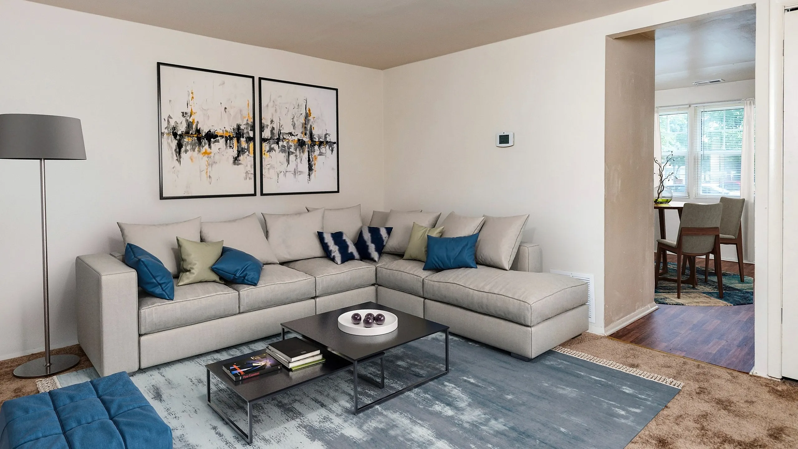 Inviting living room with a stylish L-shaped sofa, contemporary art, and elegant decor leading to sunlit dining area.