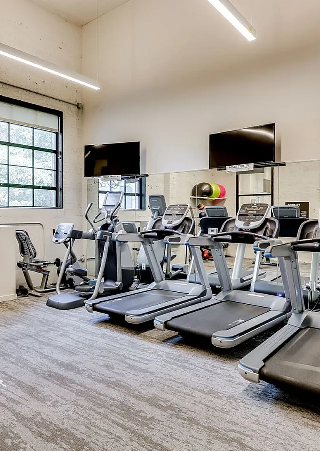 Modern fitness center with treadmills, weights, exercise balls, and a spacious layout for a complete workout experience.
