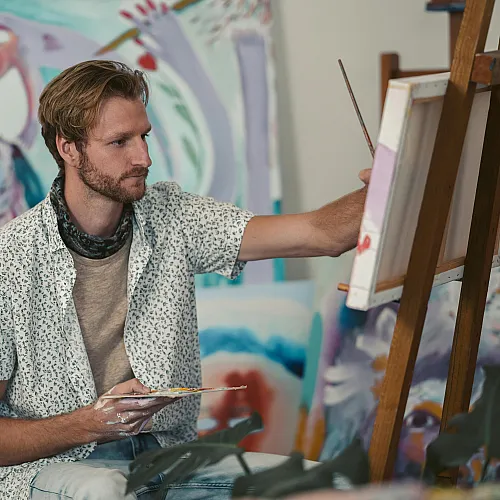 Talented artist creating vibrant abstract paintings in a colorful studio setting.