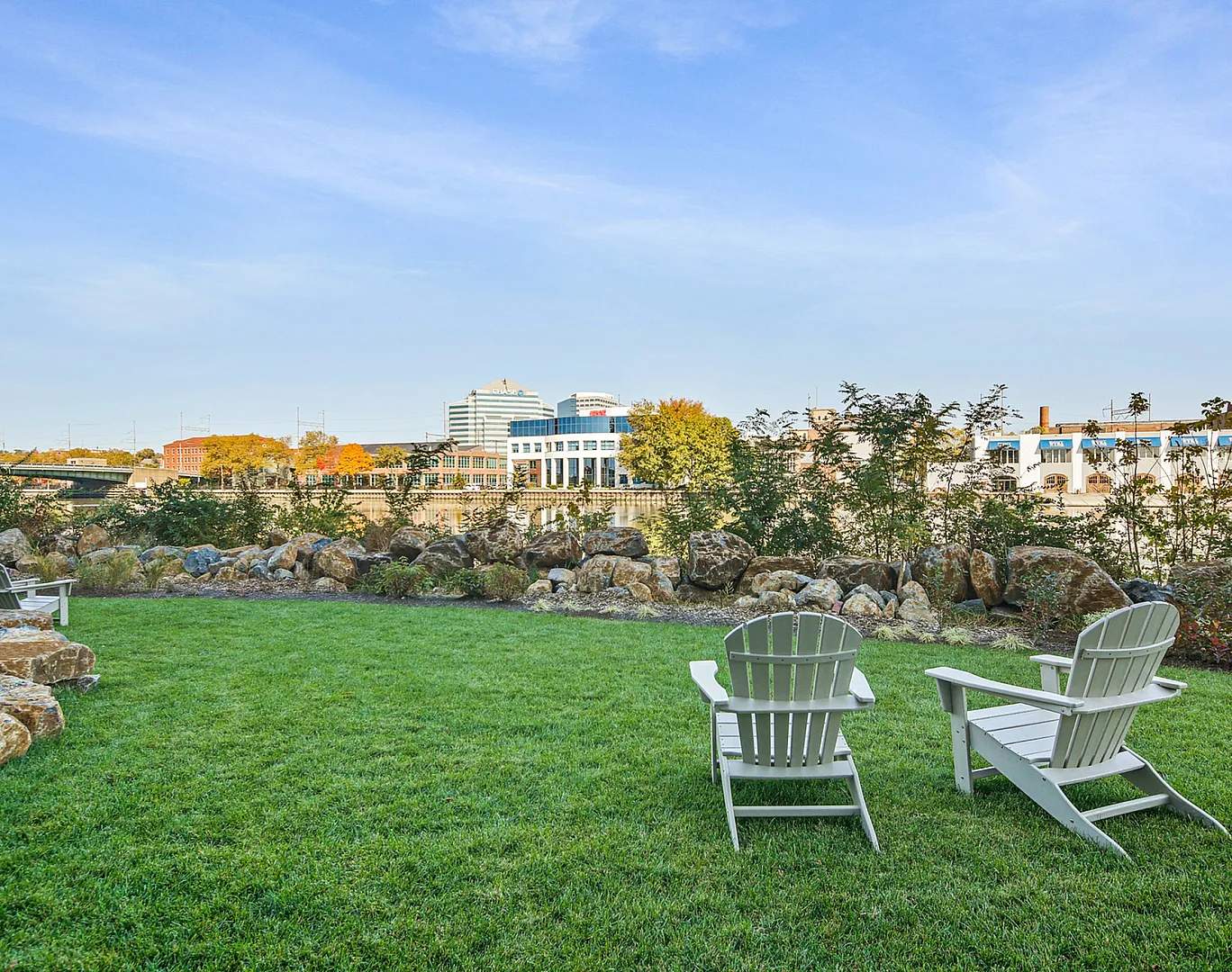 Inviting outdoor space with lush green lawn and Adirondack chairs overlooking a scenic urban skyline.