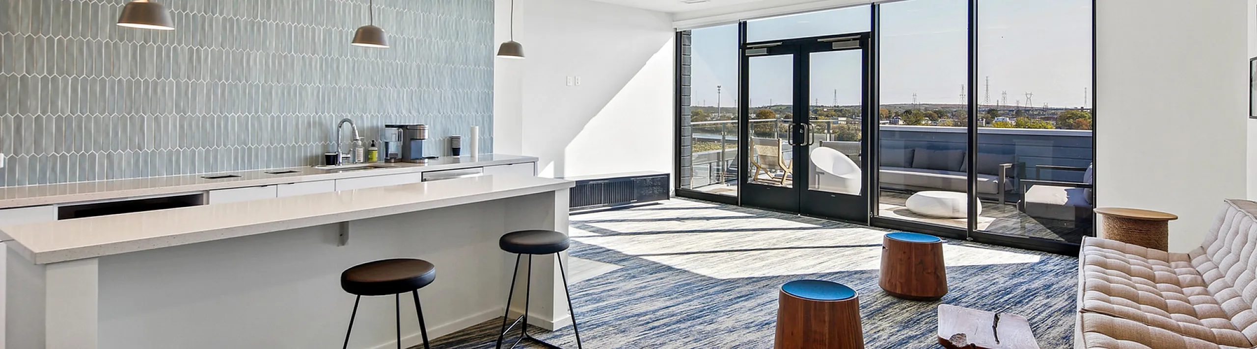 Contemporary lounge with chic bar seating, stylish pendant lights, and expansive glass doors opening to a sunlit terrace.