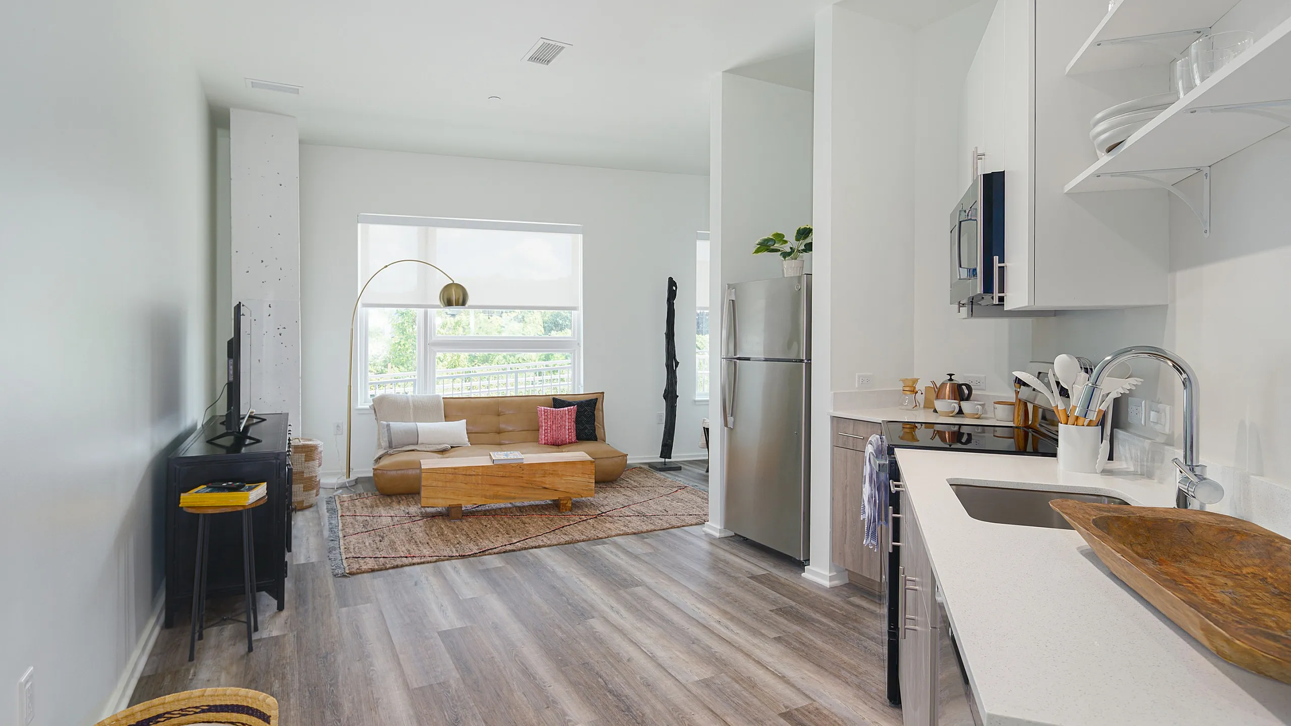 Modern apartment interior with sleek kitchen, cozy living area, and abundant natural light through large windows.