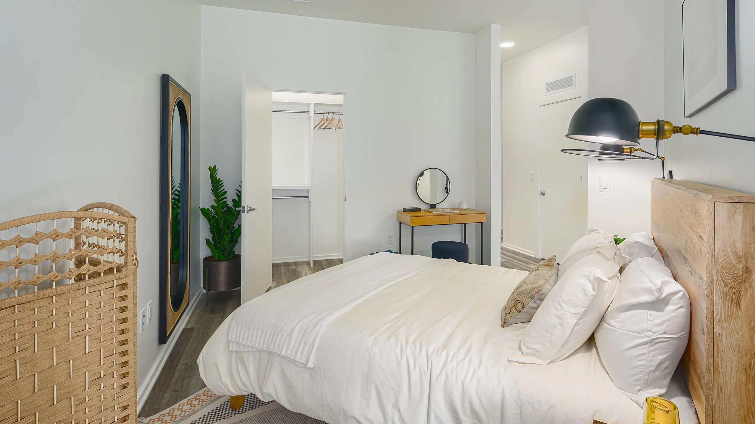 Inviting bedroom with elegant decor, featuring a cozy bed, stylish wicker screen, and spacious walk-in closet.