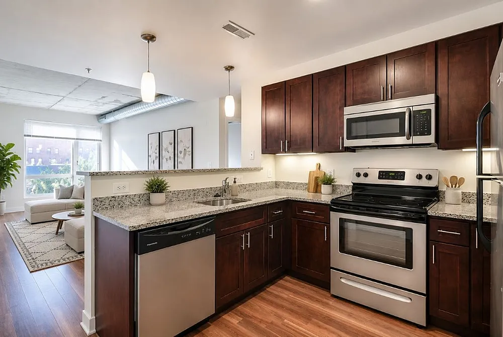 Modern open-concept kitchen with granite countertops, stainless steel appliances, and cozy living area filled with natural light.