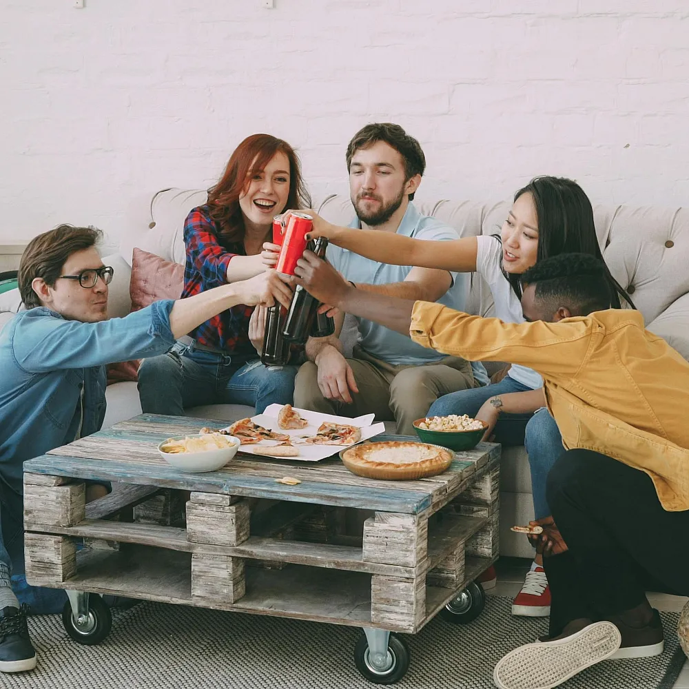 Vibrant living room scene featuring friends enjoying a cozy apartment with casual decor, plants, and a bicycle in the background.