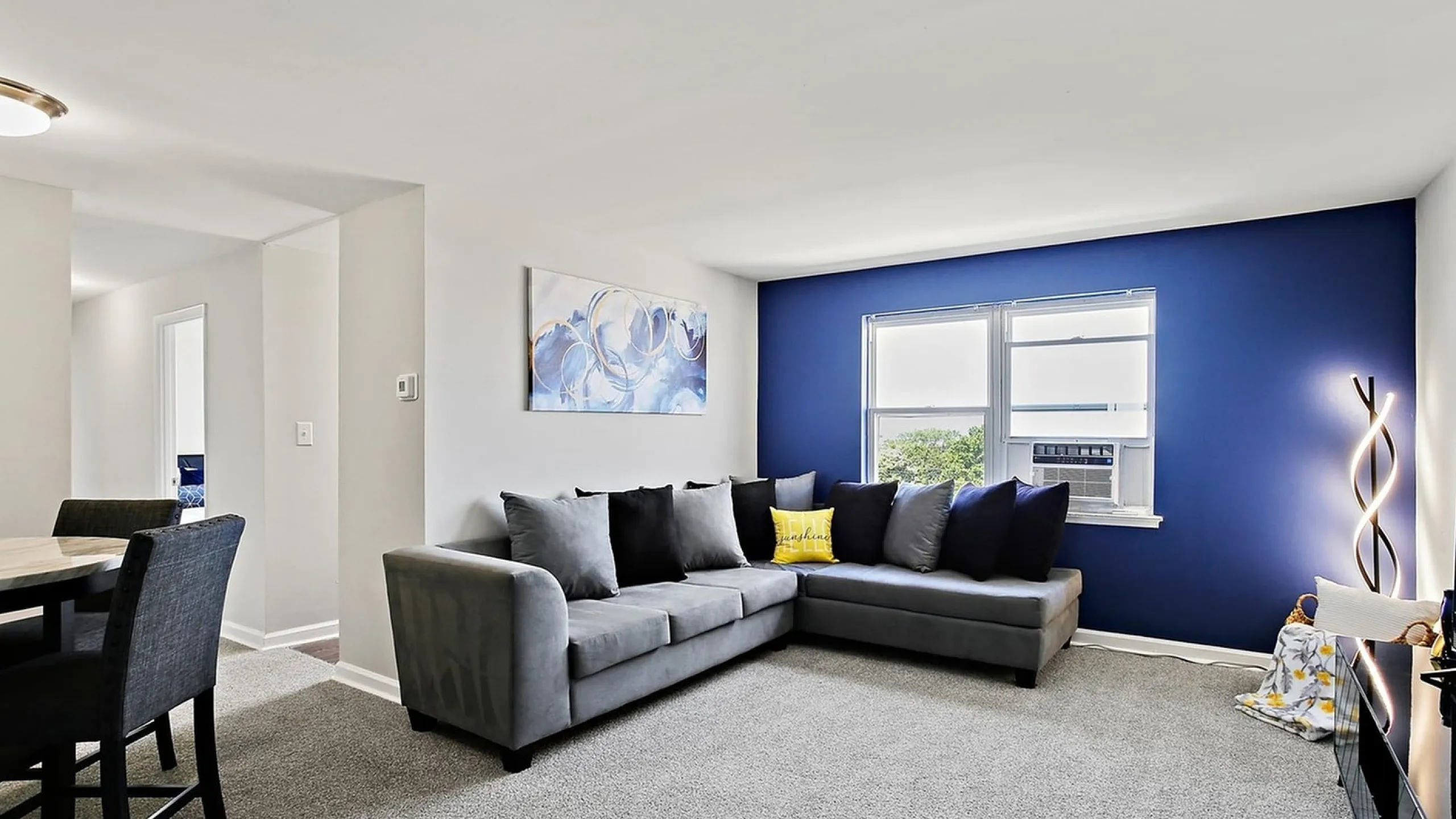 Modern living room with cozy gray sectional, vibrant blue accent wall, and elegant art piece creating a welcoming atmosphere.