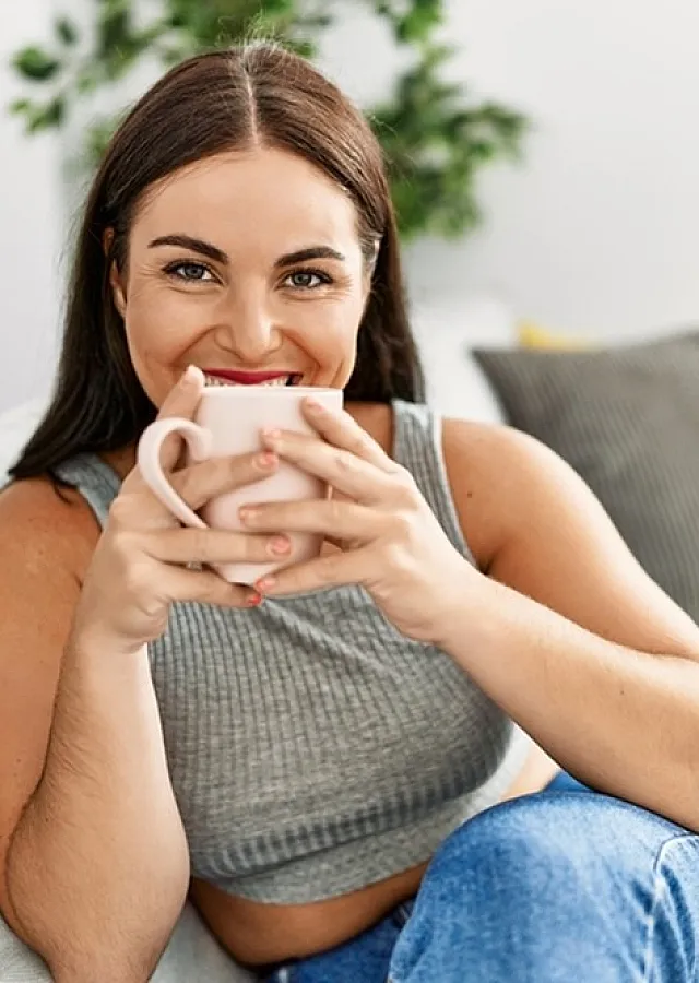 Bright and modern living space with natural light and cozy atmosphere, featuring a woman enjoying a cup of coffee by a large window.