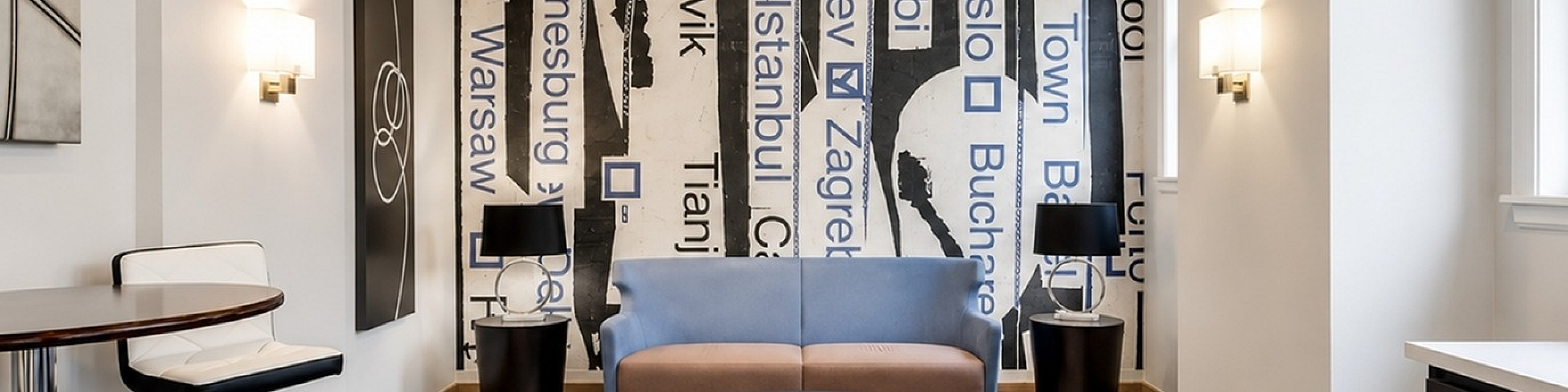 Modern lounge with chic city-themed wall art, cozy seating, and natural light from large windows.