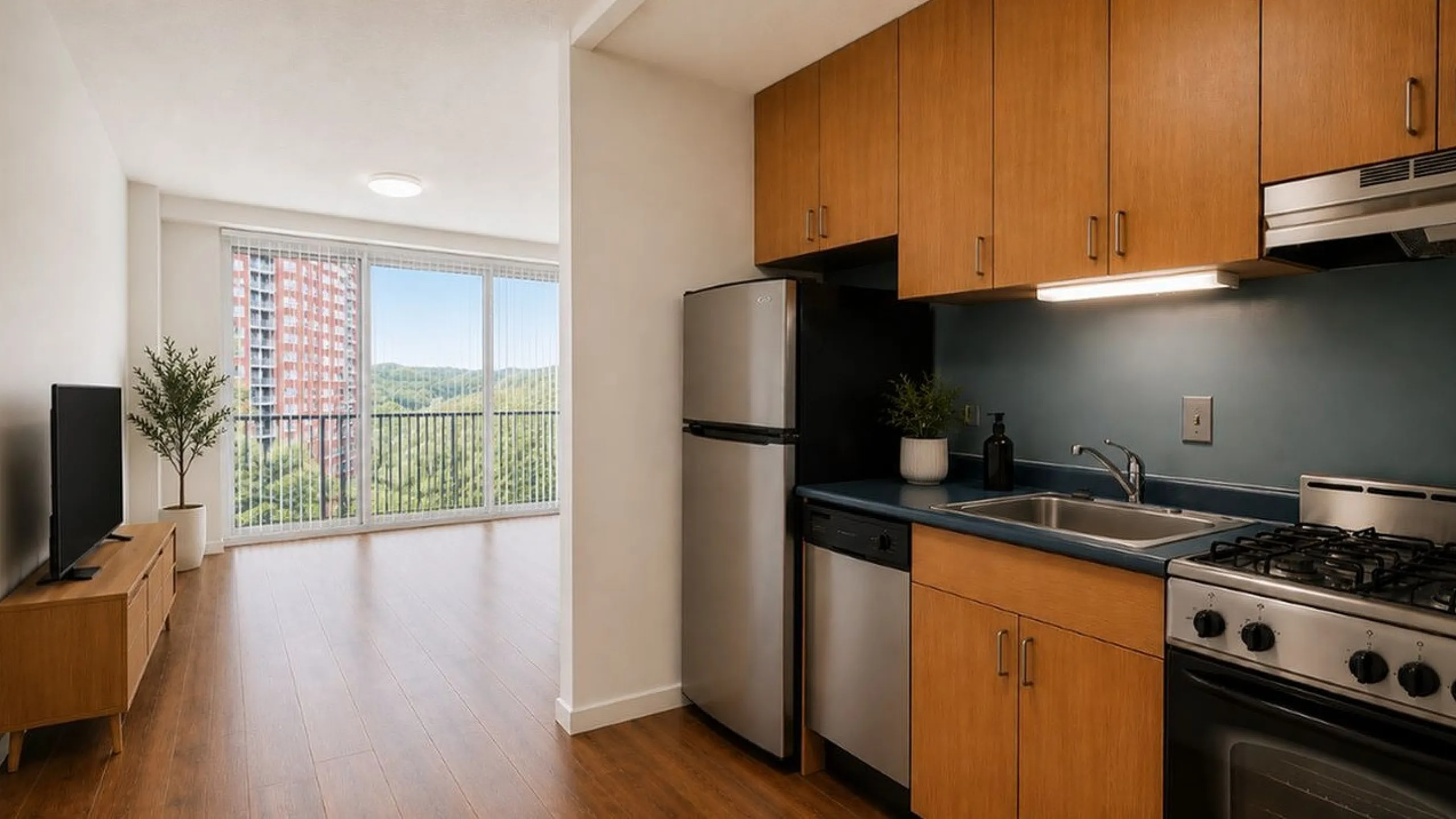 Modern apartment interior showcasing a sleek kitchen with wooden cabinets and stainless steel appliances, opening into a bright living area with a stunning view of lush greenery through expansive windows.