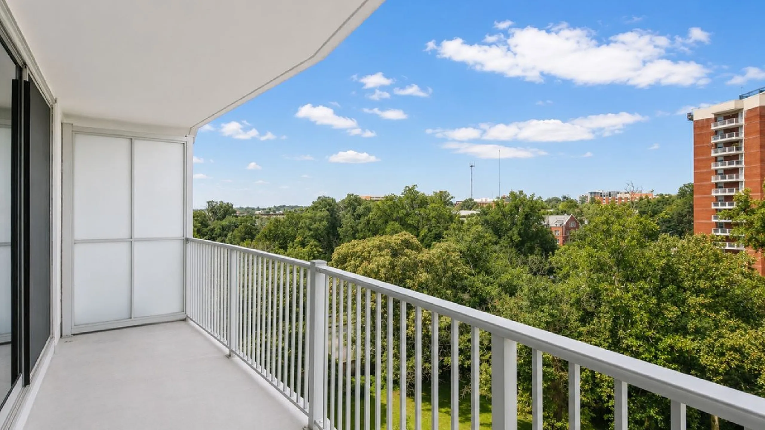 Expansive balcony with scenic views of lush trees and a vibrant cityscape, ideal for relaxation and enjoyment.