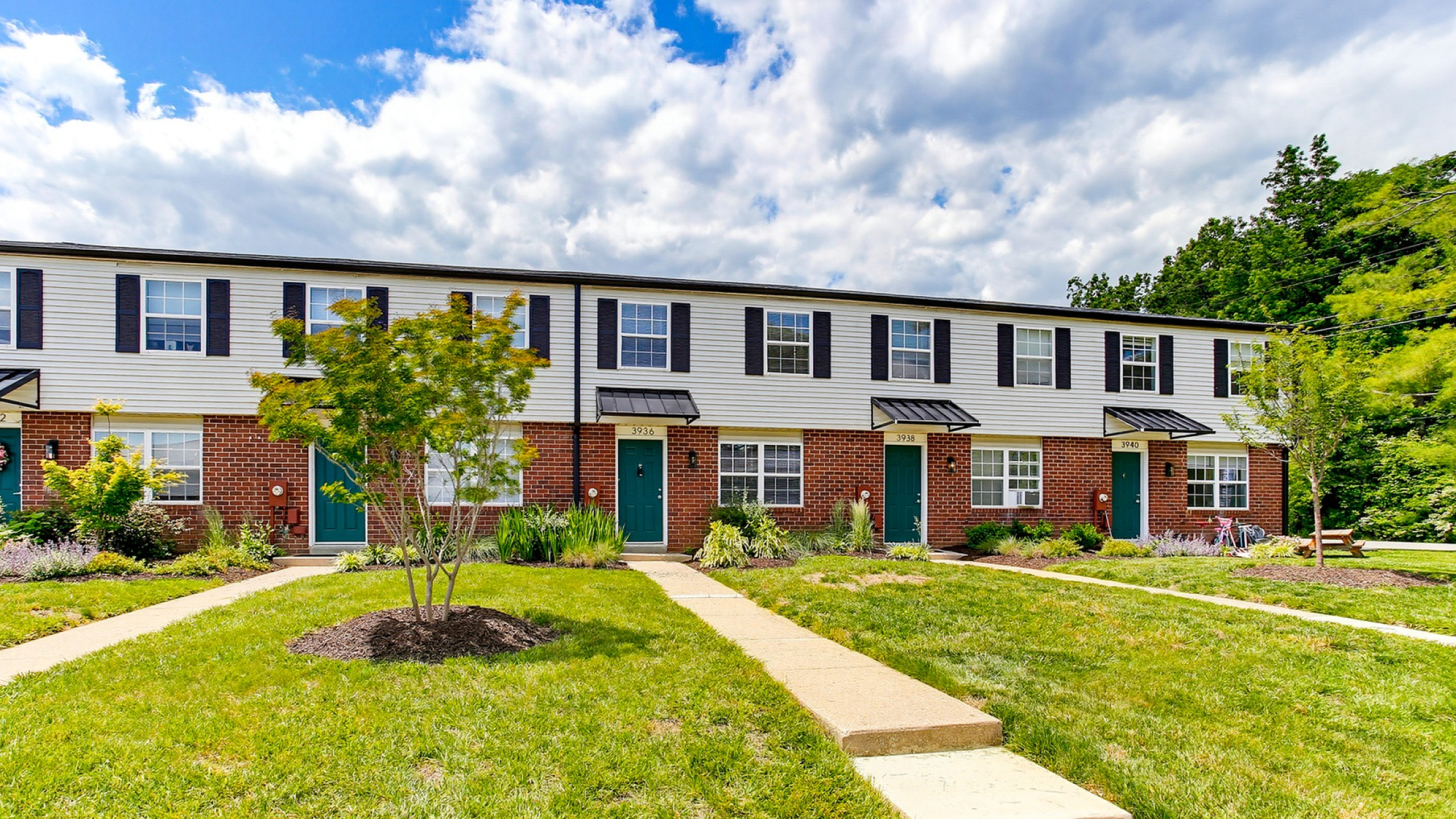 Charming townhouse row with vibrant front lawns and unique blue doors under a bright sky.
