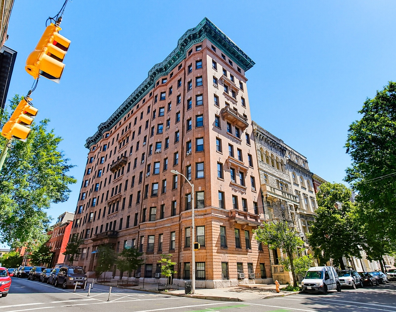 Charming historic apartment building with ornate architectural details, situated on a picturesque tree-lined street with vibrant urban energy.