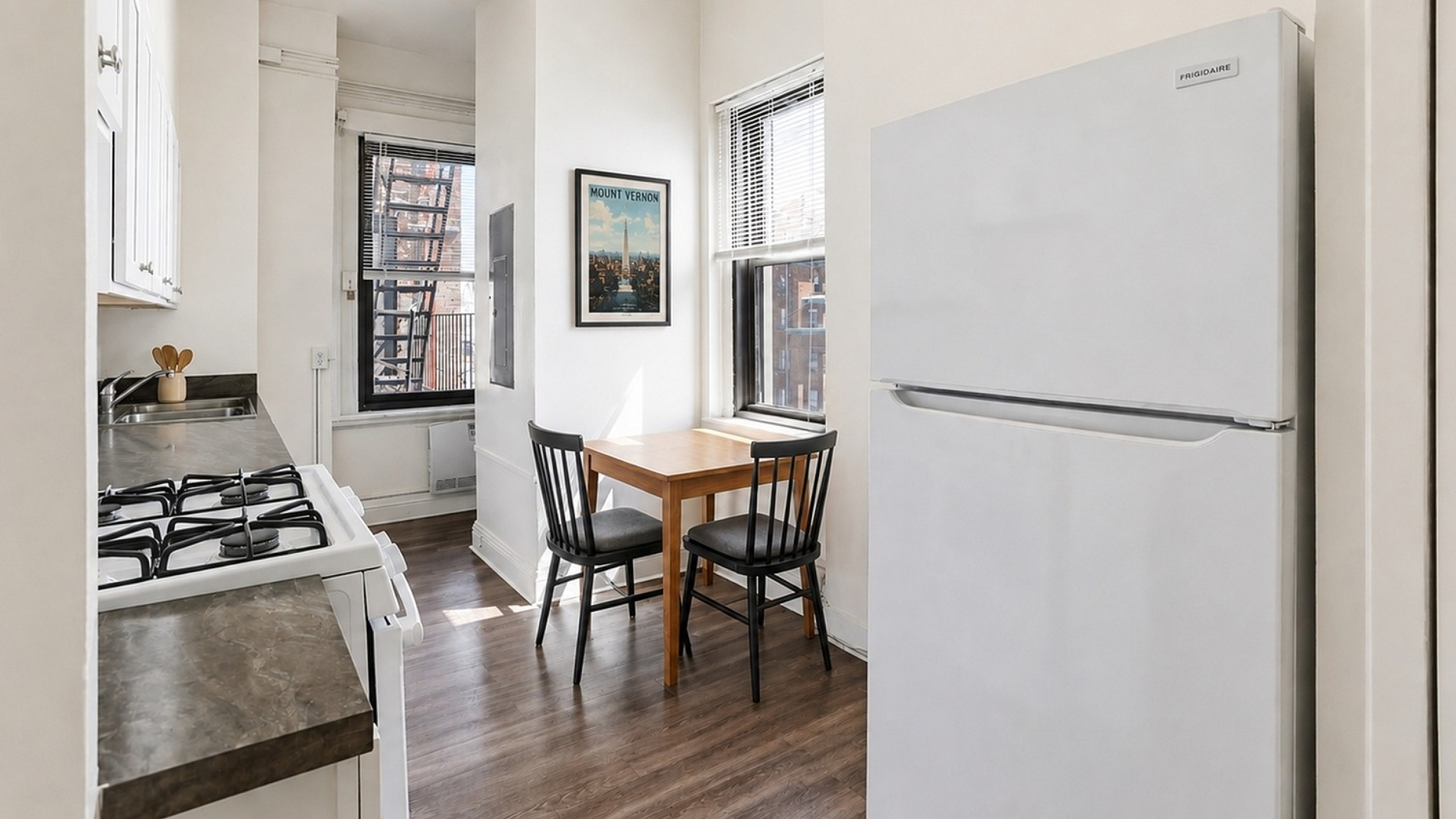 Bright, cozy kitchen with modern appliances, elegant wood flooring, and a charming breakfast nook by the window.