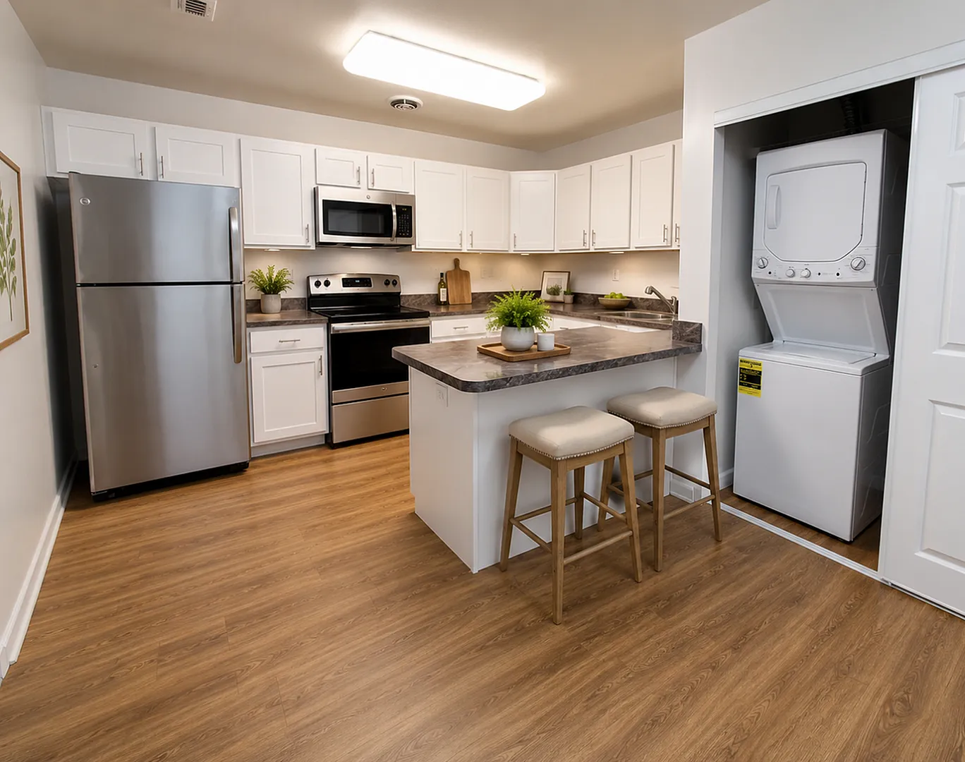 Modern kitchen with stainless steel appliances, elegant countertops, and cozy bar seating, featuring in-unit laundry for convenience.