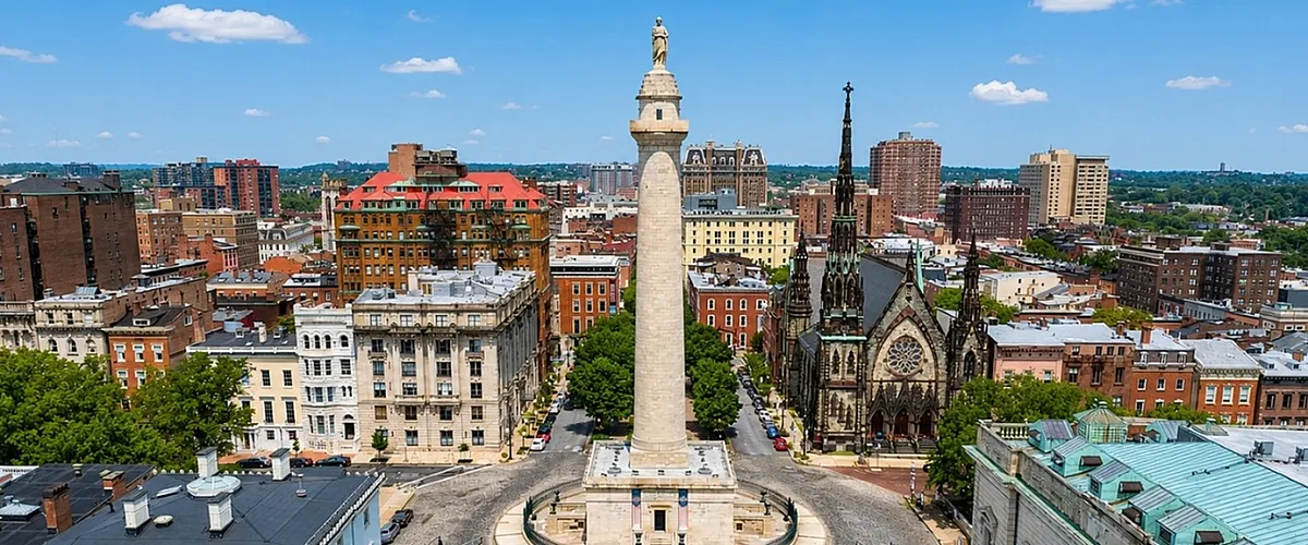 Vibrant cityscape view of a historic urban plaza with a grand monument surrounded by elegant architecture on a sunny day.