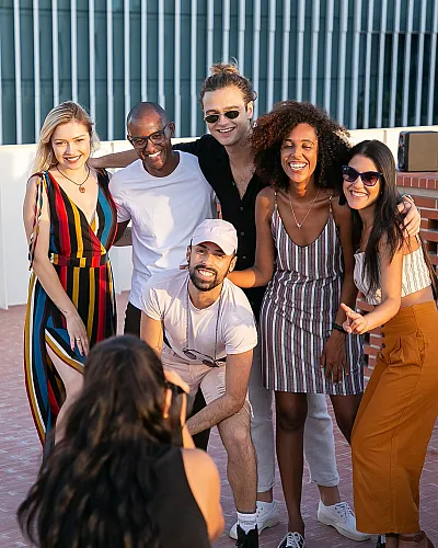 Vibrant rooftop gathering with smiling friends enjoying a sunny day, capturing the essence of community and leisure in a modern apartment setting.