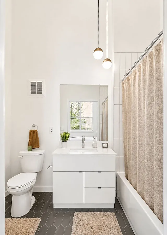 Bright, modern bathroom with elegant lighting, sleek white vanity, and large mirror offering a refreshing ambiance.