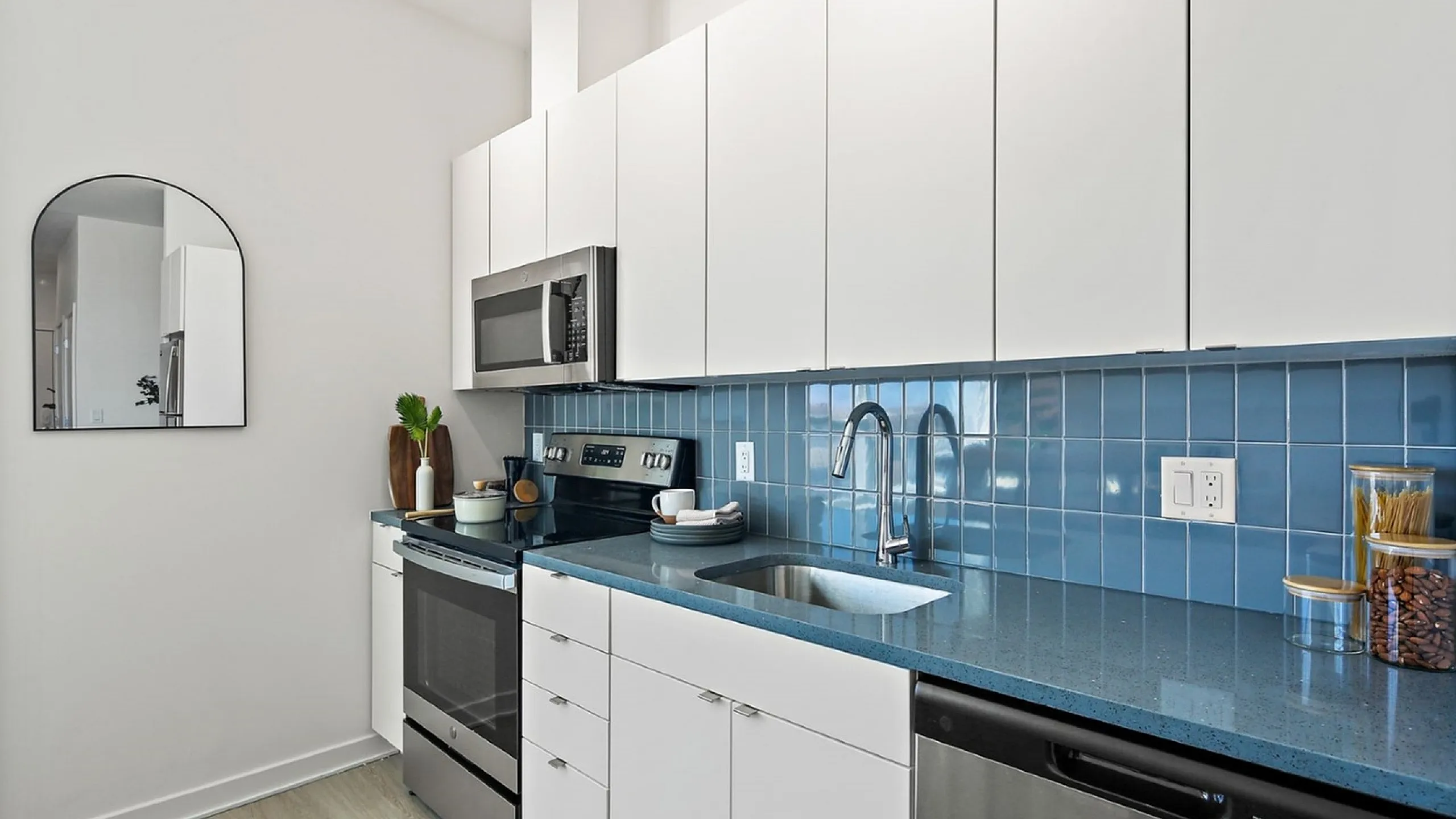 Contemporary kitchen design featuring sleek white cabinets, modern appliances, and a stylish blue tile backsplash.