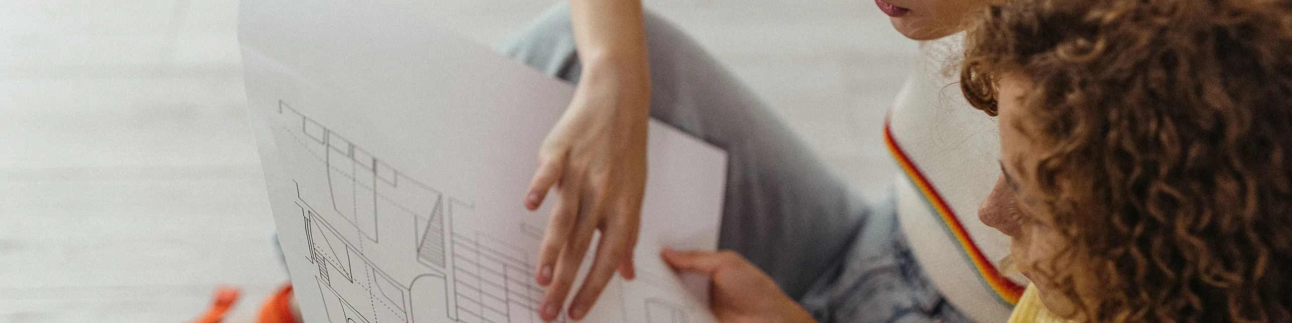 Two people discussing a modern apartment floor plan, highlighting spacious design and smart layout.